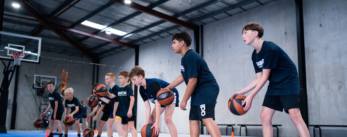 Junior players lined up with basketballs during a Coastal Basketball skills session
